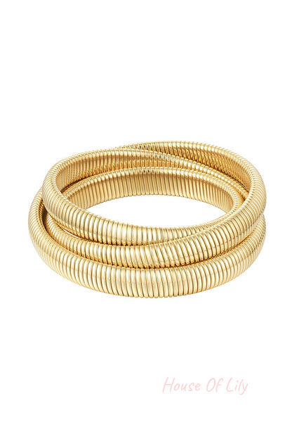 Close-up of a gold-tone triple coil wrap bracelet with ribbed texture