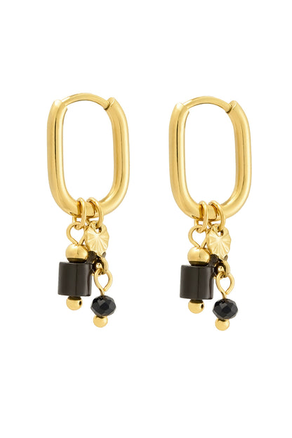 Close up of gold rectangular hoop earrings featuring dangling black stones and gold beads on white background