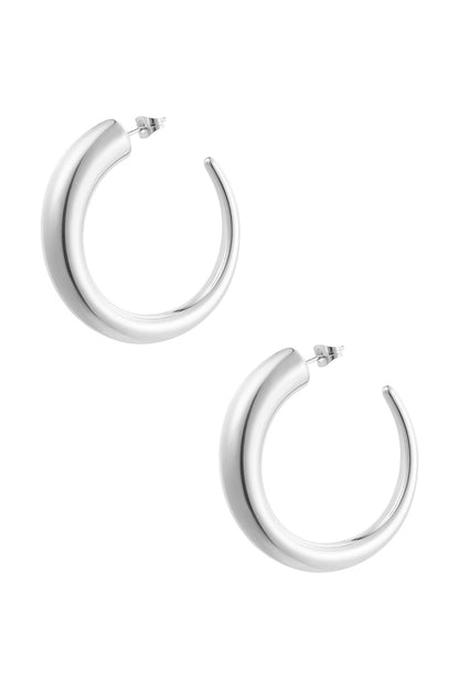 Pair of chunky silver curved hoop earrings on white background
