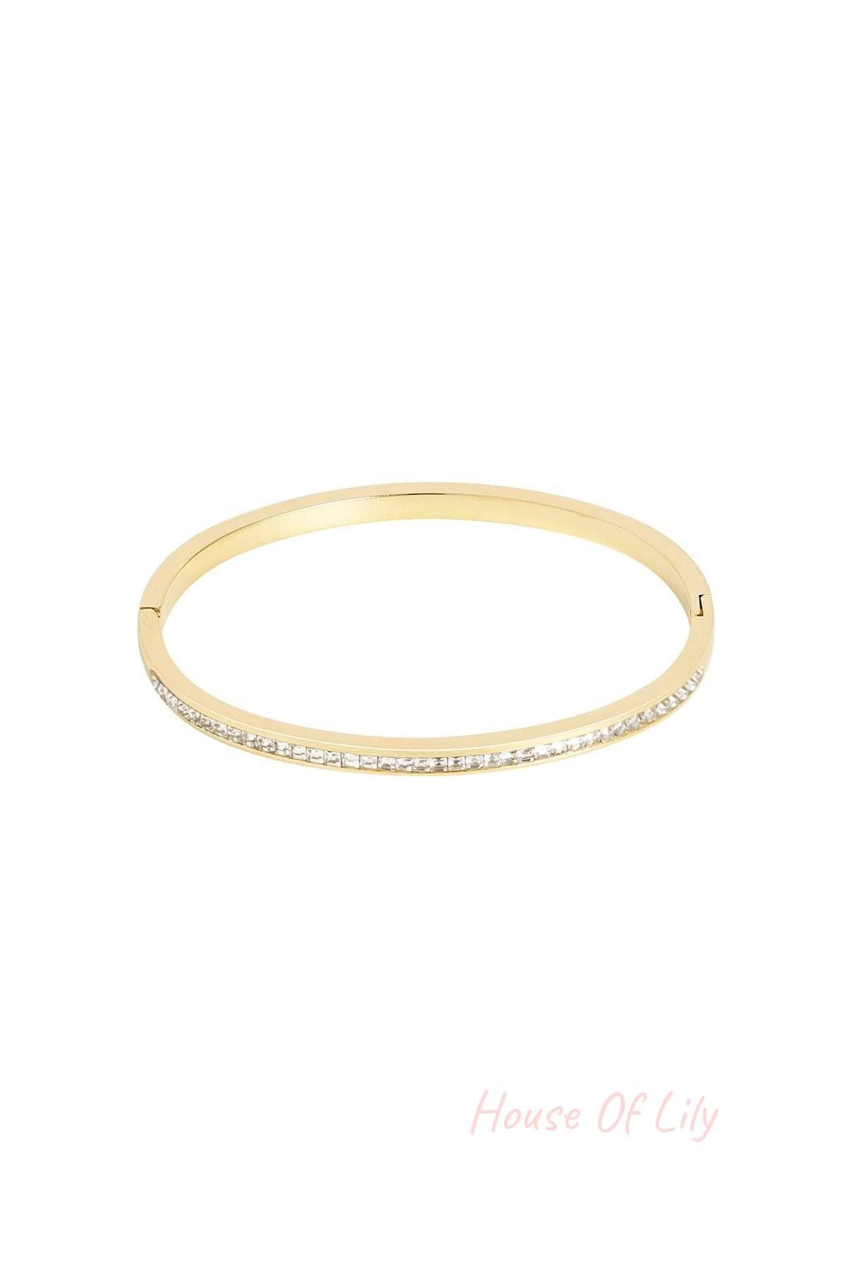 Gold-tone bangle bracelet with embedded clear crystals on white background