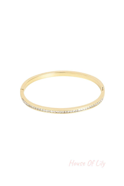 Gold-tone bangle bracelet with embedded clear crystals on white background
