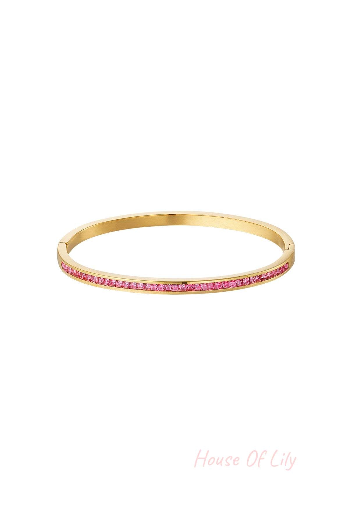 Gold-tone bangle bracelet with embedded pink crystals on white background