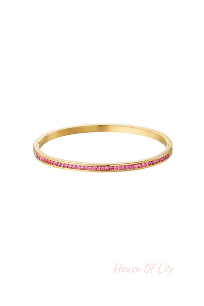 Gold-tone bangle bracelet with embedded pink crystals on white background