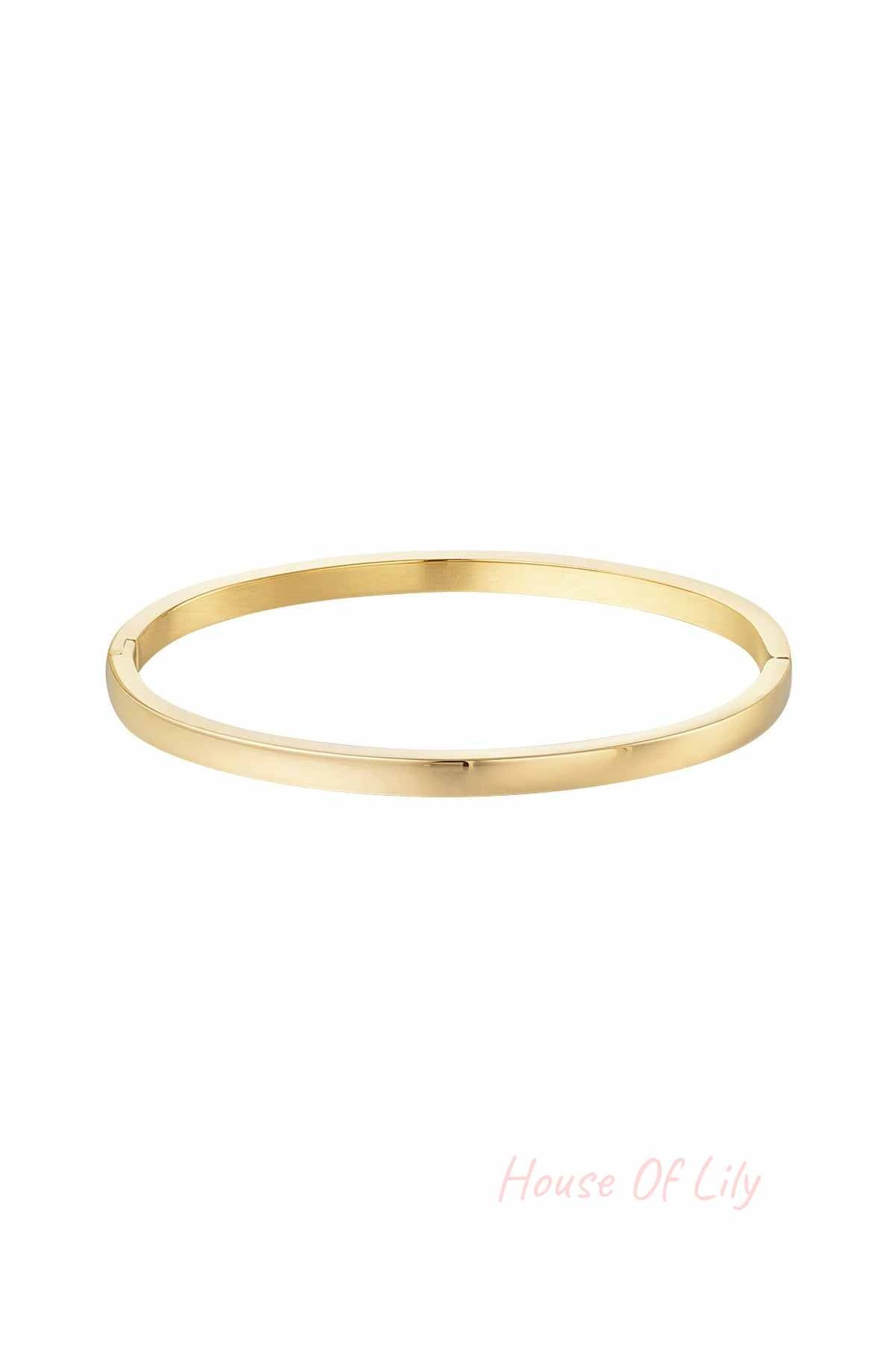 Single polished slim gold bangle bracelet on white background