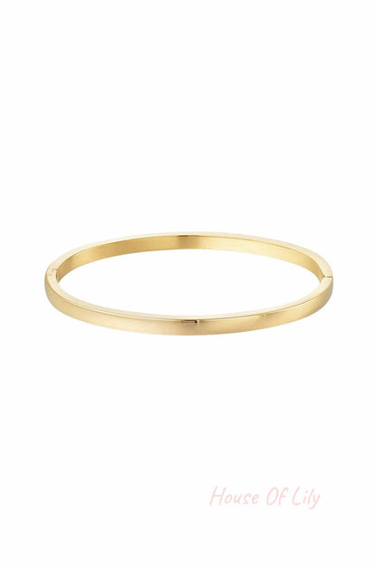 Single polished slim gold bangle bracelet on white background