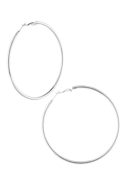 Pair of polished silver-colored large hoop earrings with hinged clasp on a white background