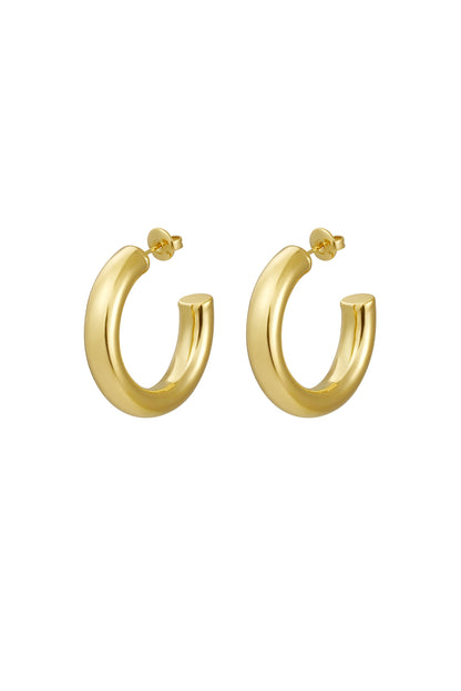 Pair of shiny chunky gold hoop earrings with thick rounded design on white background