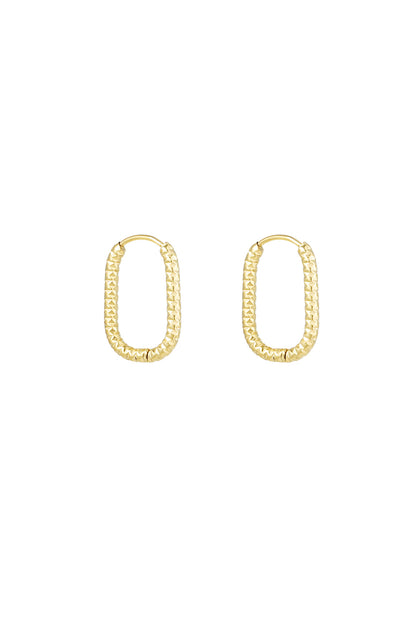 Pair of gold textured oval hoop earrings on white background