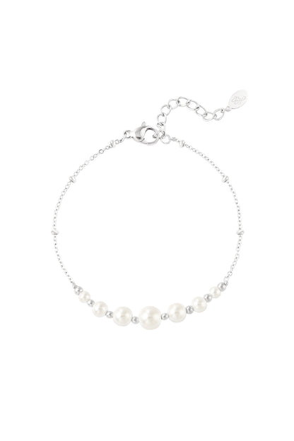 Close-up of a delicate silver chain bracelet with white pearl beads and small silver beads on a white background