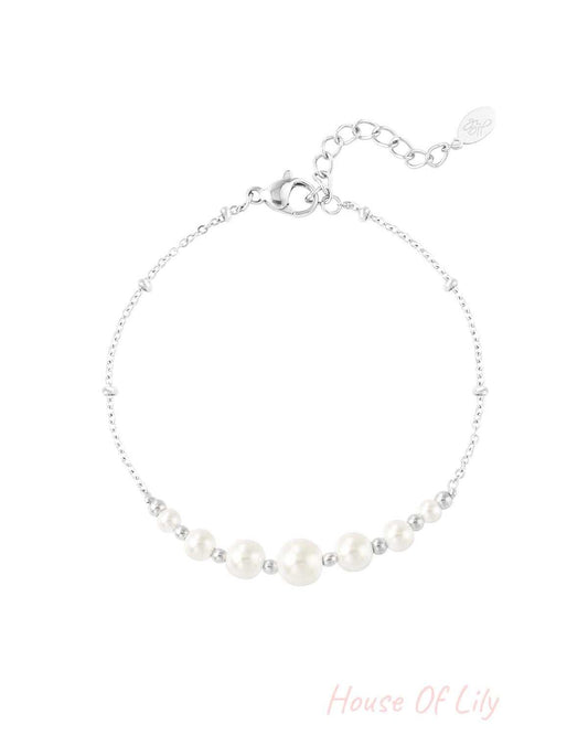 Close-up of a delicate silver chain bracelet with white pearl beads and small silver beads on a white background