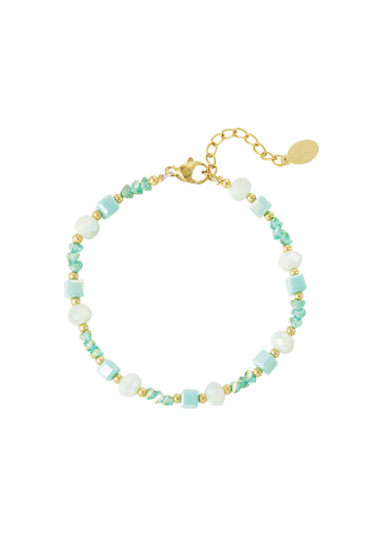 Close-up of a beaded bracelet with pastel blue, mint green, white glass beads and gold accents on a white background
