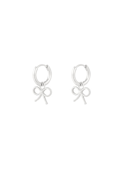 Pair of silver hoop earrings with textured bow charms on white background