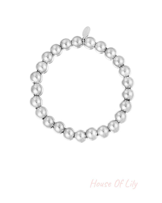 Silver beaded bracelet with polished round beads arranged in a circle with a small tag against white background