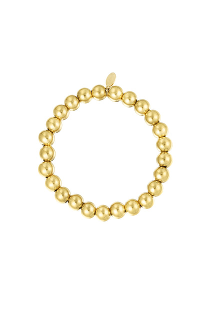 Gold beaded bracelet with polished round beads arranged in a circle with a small tag against white background