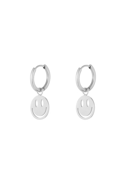 Silver-tone version of the hoop earrings with dangling smiley face charms on a white background