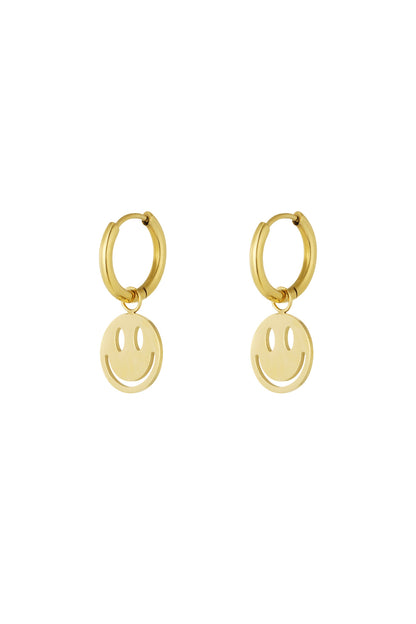 Pair of gold-tone hoop earrings each with a dangling smiley face charm against a white background