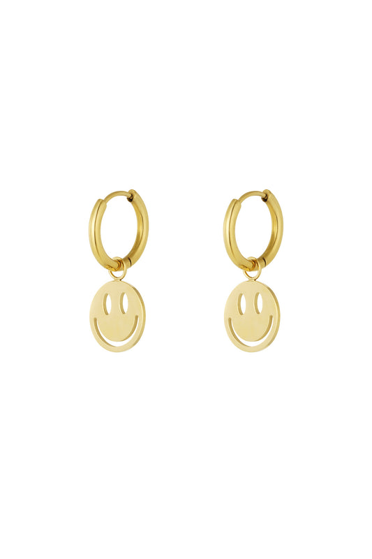 Pair of gold-tone hoop earrings each with a dangling smiley face charm against a white background