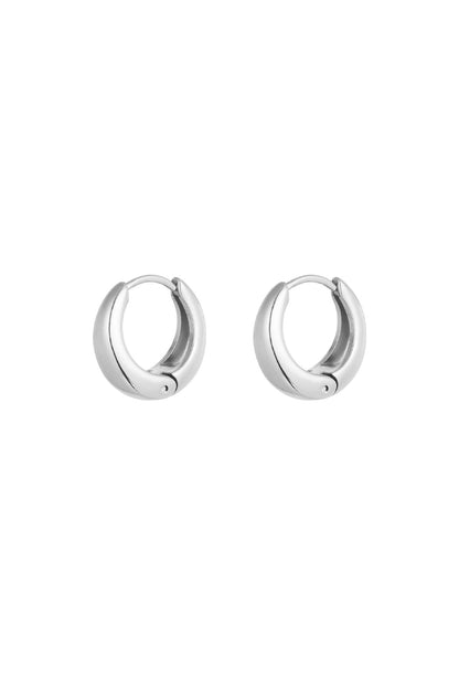 Pair of chunky silver stainless steel hoop earrings with hinge closure on white background