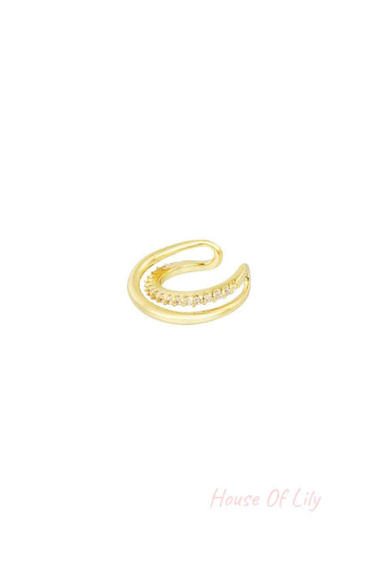 Gold spiral ear cuff with a row of sparkling zirconia stones on a white background