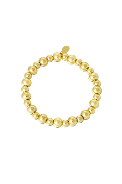 Golden beaded bracelet with alternating large and small polished round beads arranged in a circle on white background