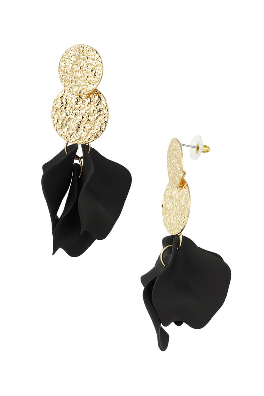 Close-up of drop earrings with textured gold discs and black soft petal shapes