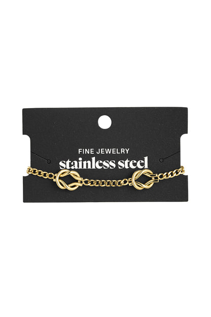 Gold knot bracelet displayed on black fine jewelry card with stainless steel branding