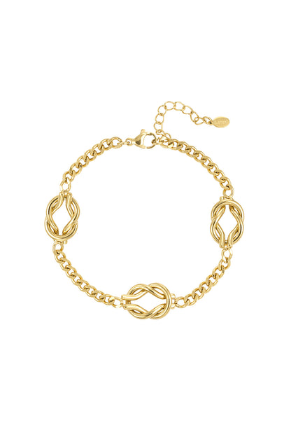 Close-up of a gold stainless steel bracelet with three twisted knot charms and adjustable chain clasp on white background