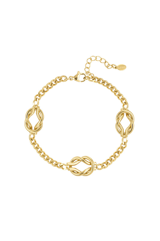 Close-up of a gold stainless steel bracelet with three twisted knot charms and adjustable chain clasp on white background