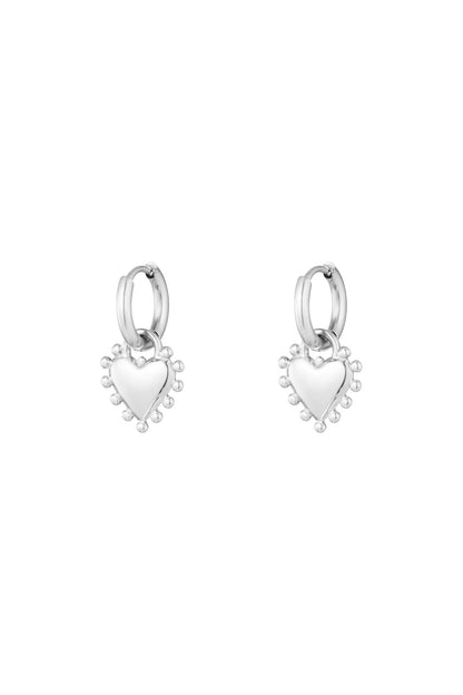 Pair of silver heart charm hoop earrings with beaded edge detail on white background