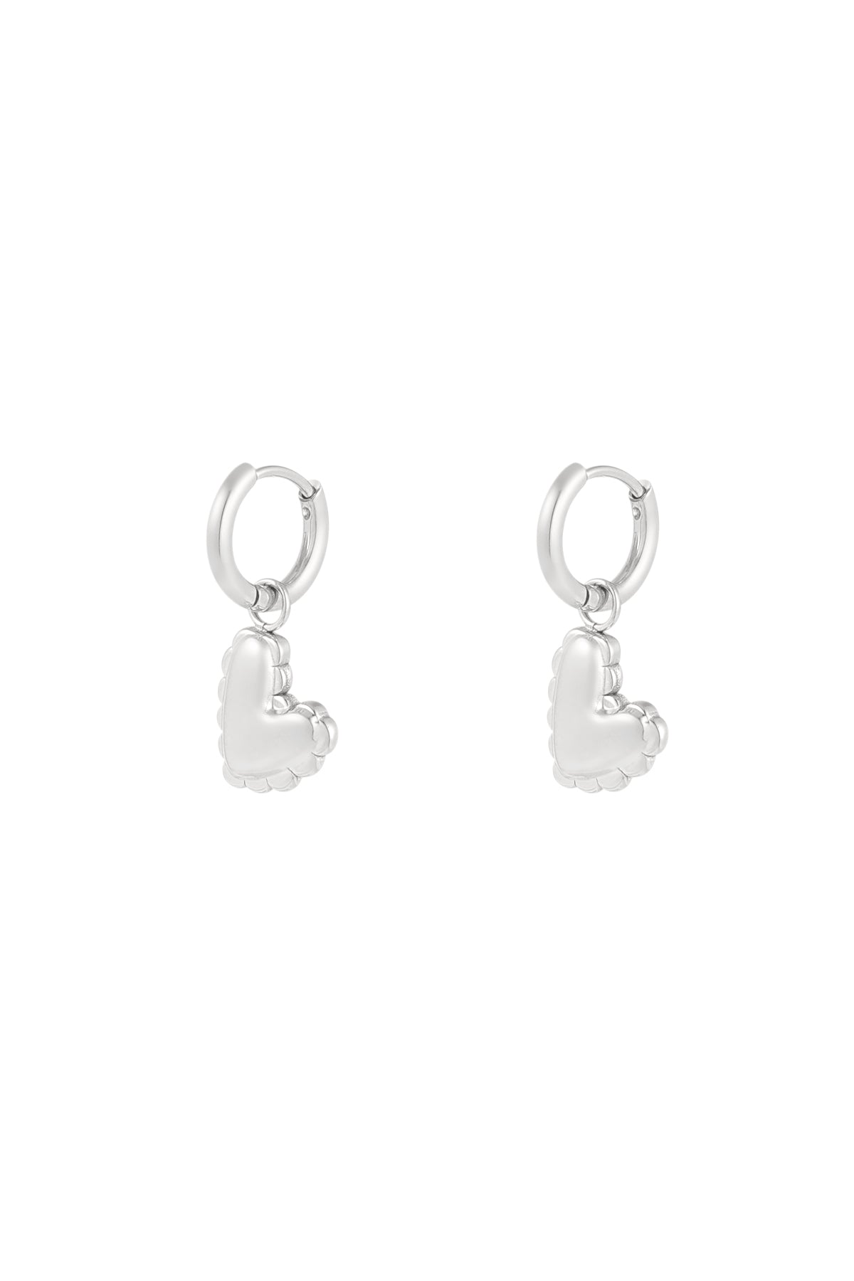 Close-up of silver heart charm drop earrings with scalloped puffed heart design against white background