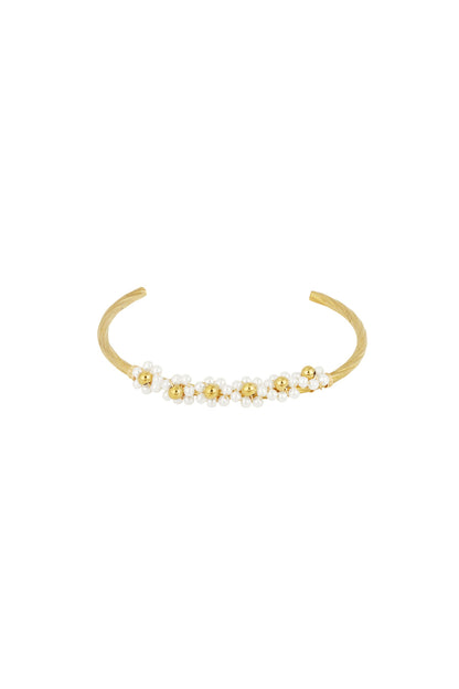 Close-up of a gold-tone open cuff bracelet adorned with clusters of small imitation pearls arranged like flowers.