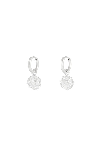 Silver hoop earrings with detailed daisy flower charms on a plain white background