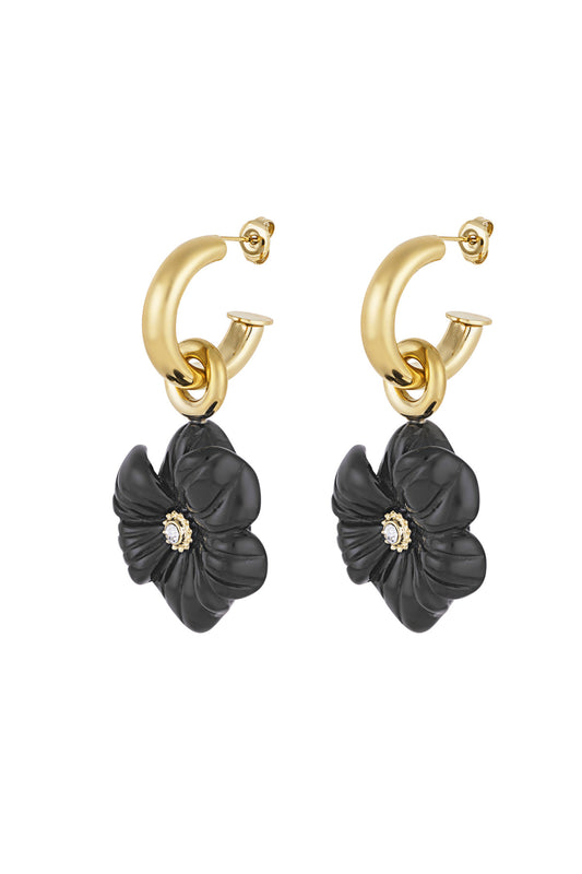 Pair of gold-tone hoop earrings with black flower charm and rhinestone center on white background
