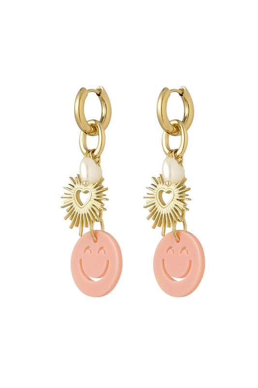 Pair of gold-tone drop earrings with peach smiley face acrylic charms, sunburst heart pendants, and white pearl heart details