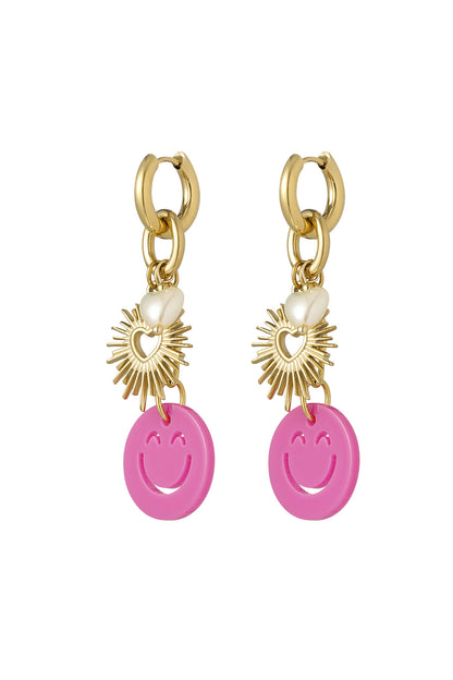 Pair of gold-tone drop earrings featuring smiley face pink acrylic charms, gold sunburst heart pendants, and small pearl heart accents