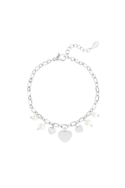 Silver-tone charm bracelet with heart and pearl charms on plain white background.