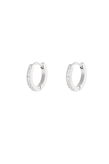 Pair of silver mini hoop earrings decorated with sparkling clear stones shown on white background