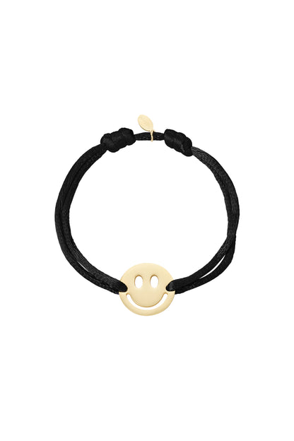 Pink satin cord bracelet with gold-tone smiley face charm on white background