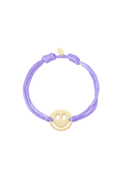 Green satin cord bracelet with gold-tone smiley face charm on white background