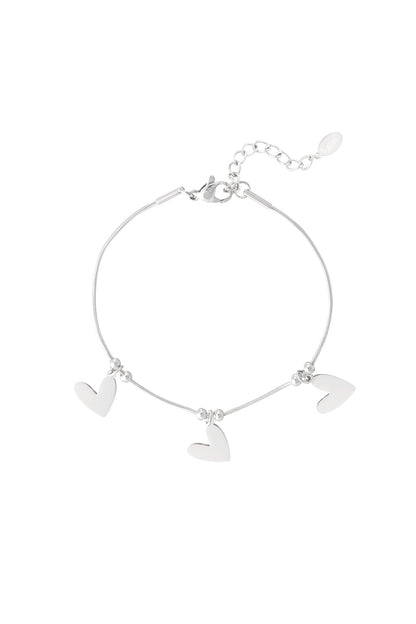 Silver heart charm bracelet with three flat heart pendants and adjustable chain on white background