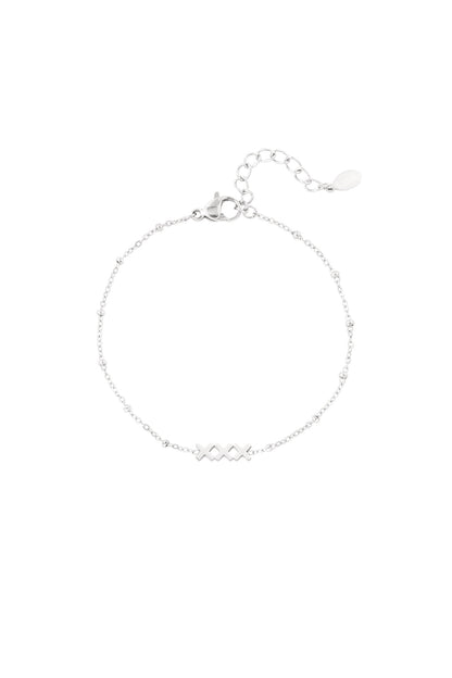Close-up of a silver version of the minimalist 'XXX' charm bracelet on white background