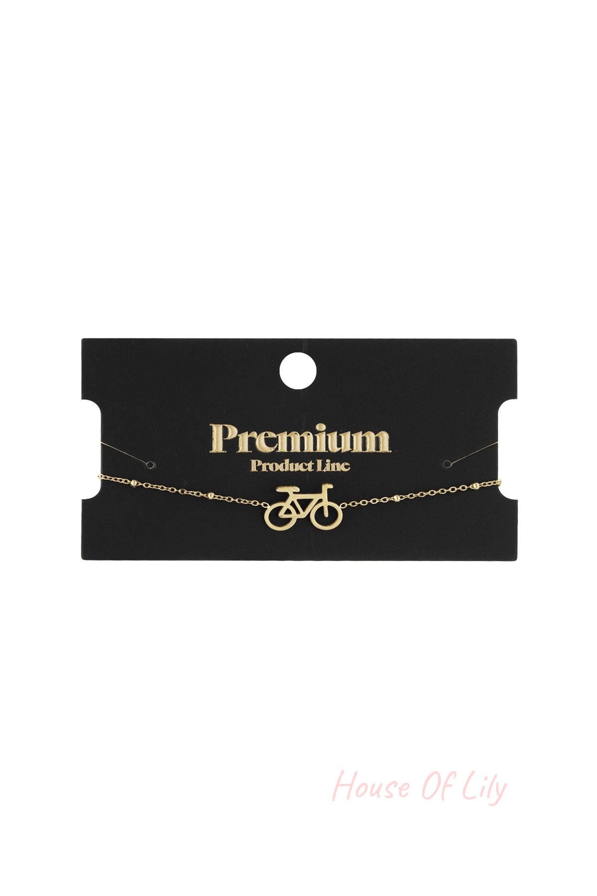 Gold bicycle charm bracelet displayed on black packaging reading 'Premium Product Line'