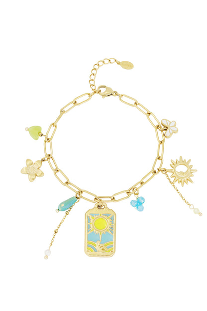Gold-tone chain charm bracelet with sun, flower, butterfly, blue beads and pearl charms on a white background