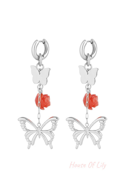 Silver butterfly and rose drop earrings close-up on white background