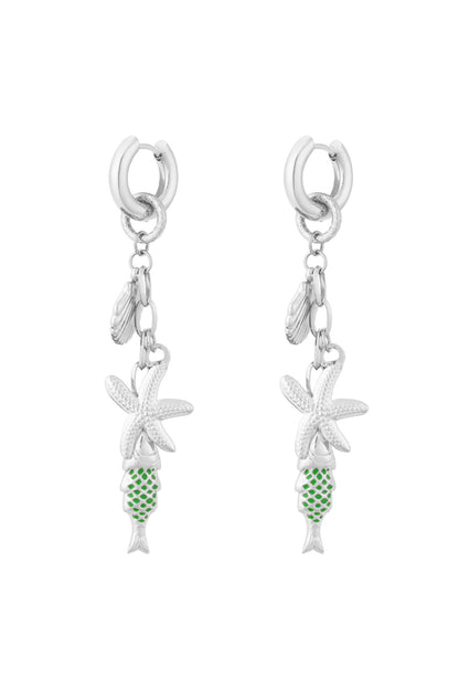 Pair of silver-tone drop earrings featuring starfish, seashell and green enamel fish charms on white background