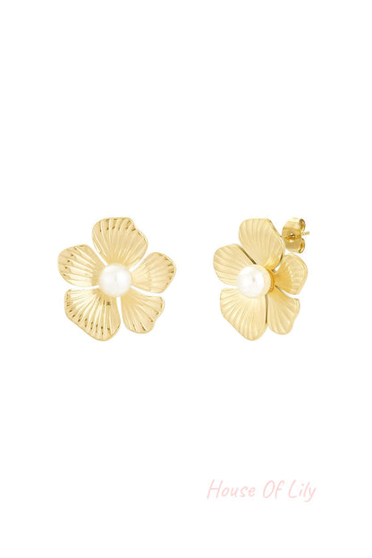 Close-up of gold-tone flower-shaped stud earrings with a central white pearl on a white background