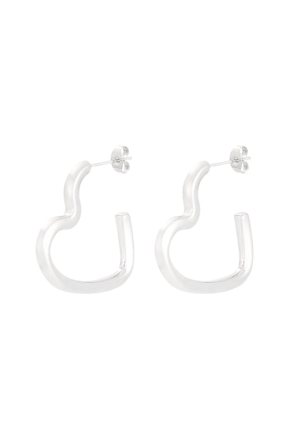 Pair of silver-toned wavy heart-shaped hoop earrings on white background