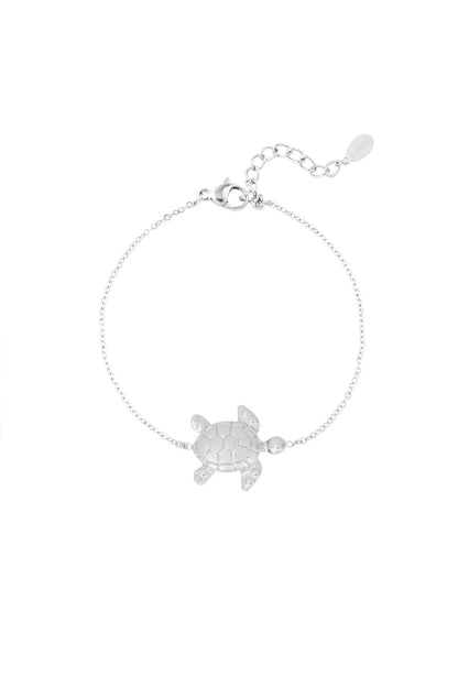 Close-up of a delicate silver bracelet featuring a detailed turtle charm with an adjustable chain clasp