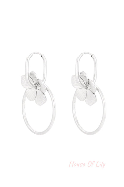 Pair of silver-tone floral hoop drop earrings with flower charms and circular hoops on white background