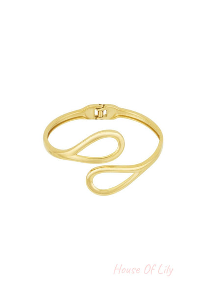 Gold-toned cuff bracelet with open loop design on white background